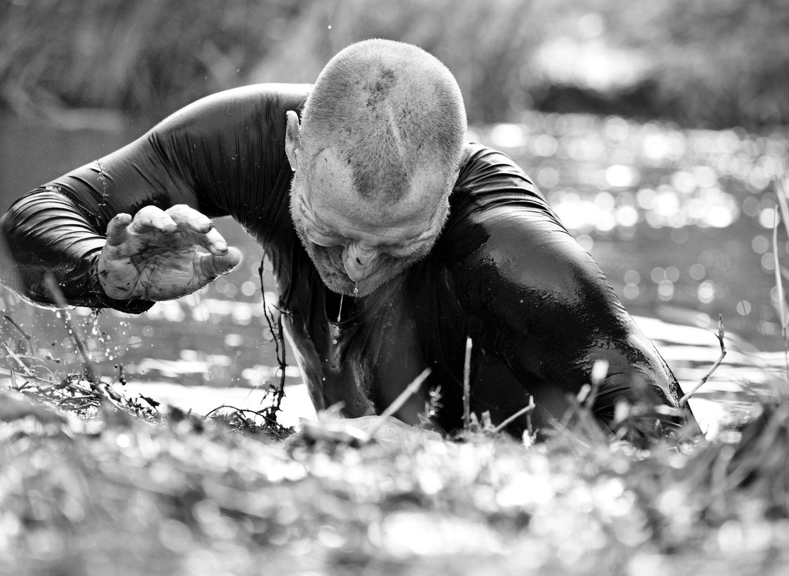 Man climbing out of water obstacle at mud run